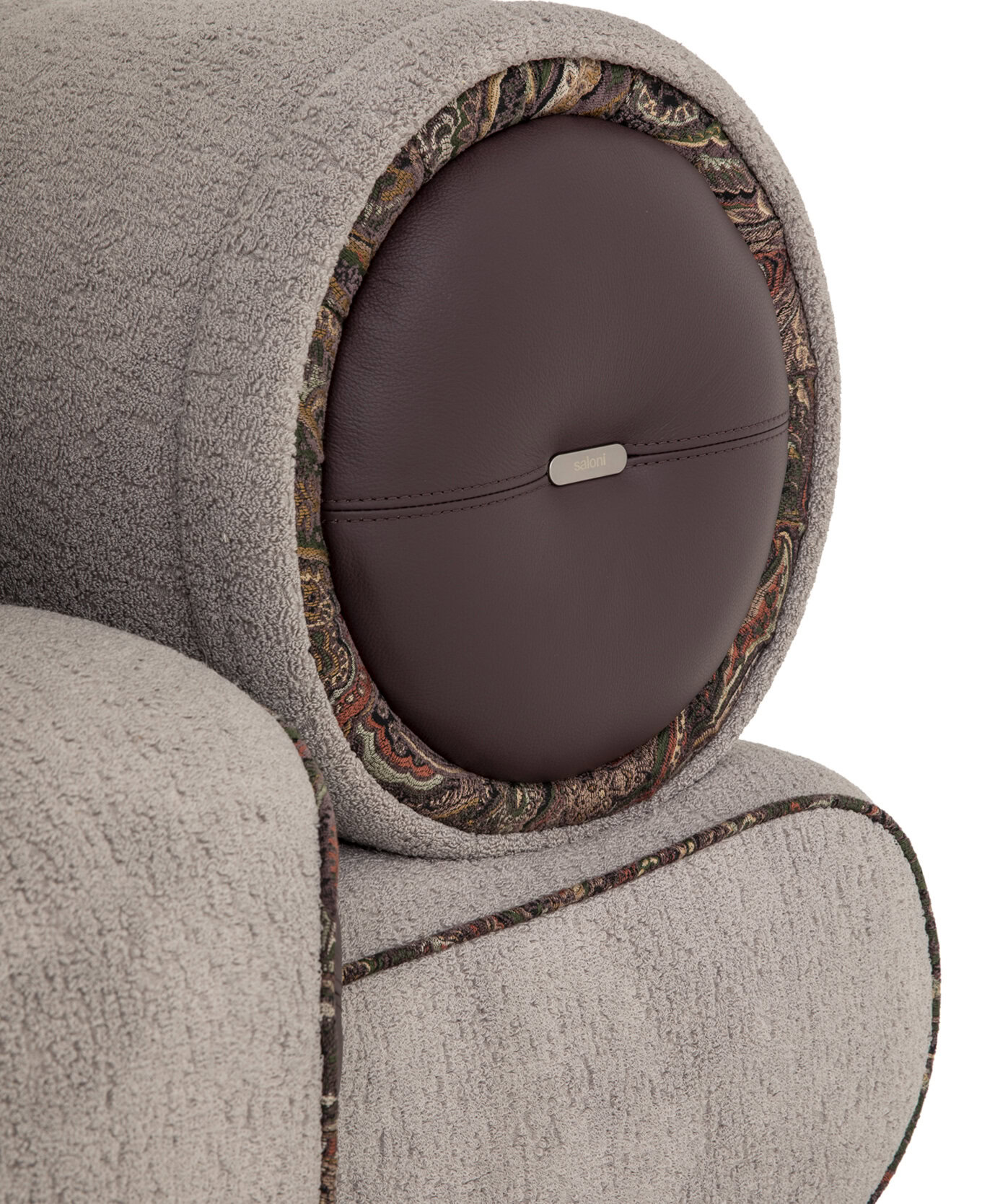 Elegant beige textured fabric sofa with a unique rounded backrest featuring a decorative paisley-patterned trim and leather accent with "saloni" branding, blending modern style with classic comfort.