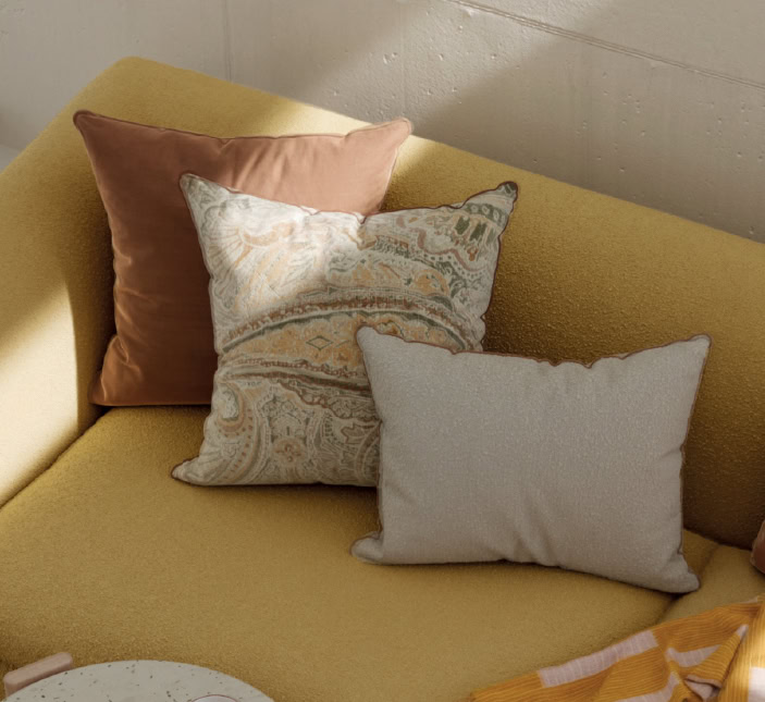 Elegant throw pillows with varied textures and patterns on a mustard yellow sofa, perfect for enhancing comfort and style in modern living spaces.