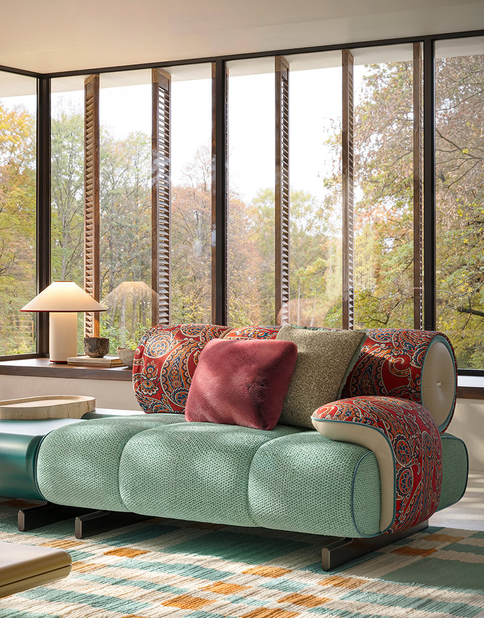 Stylish modern sofa featuring vibrant cushions in a bright, airy room with large floor-to-ceiling windows overlooking a lush, green outdoor landscape. Perfect for contemporary living spaces.