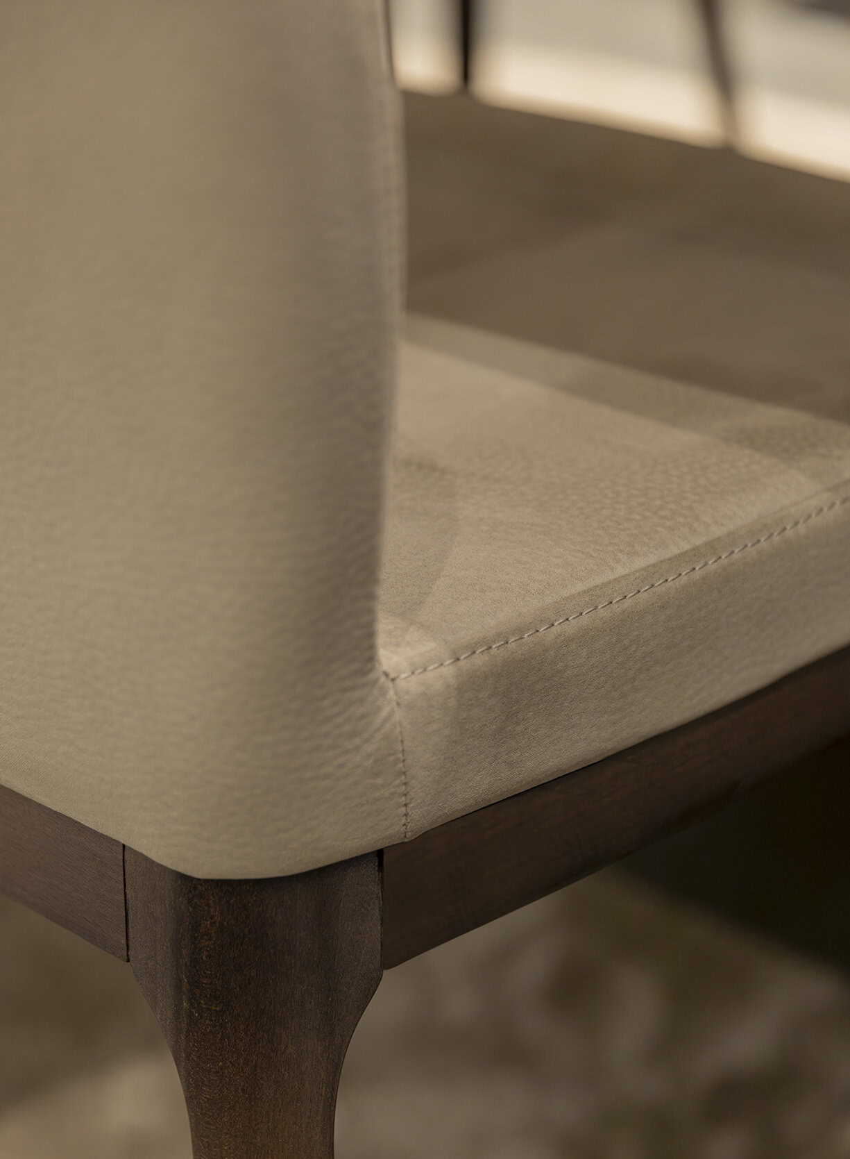 Elegant beige upholstered armchair with dark wooden accents, showcasing luxurious comfort and classic design elements, ideal for sophisticated living spaces.