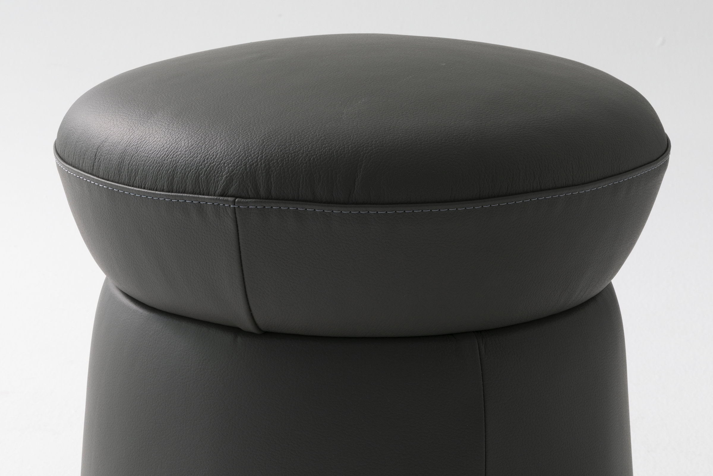 Luxurious black leather ottoman with cushioned top and sturdy base, perfect for modern living room decor and comfort.