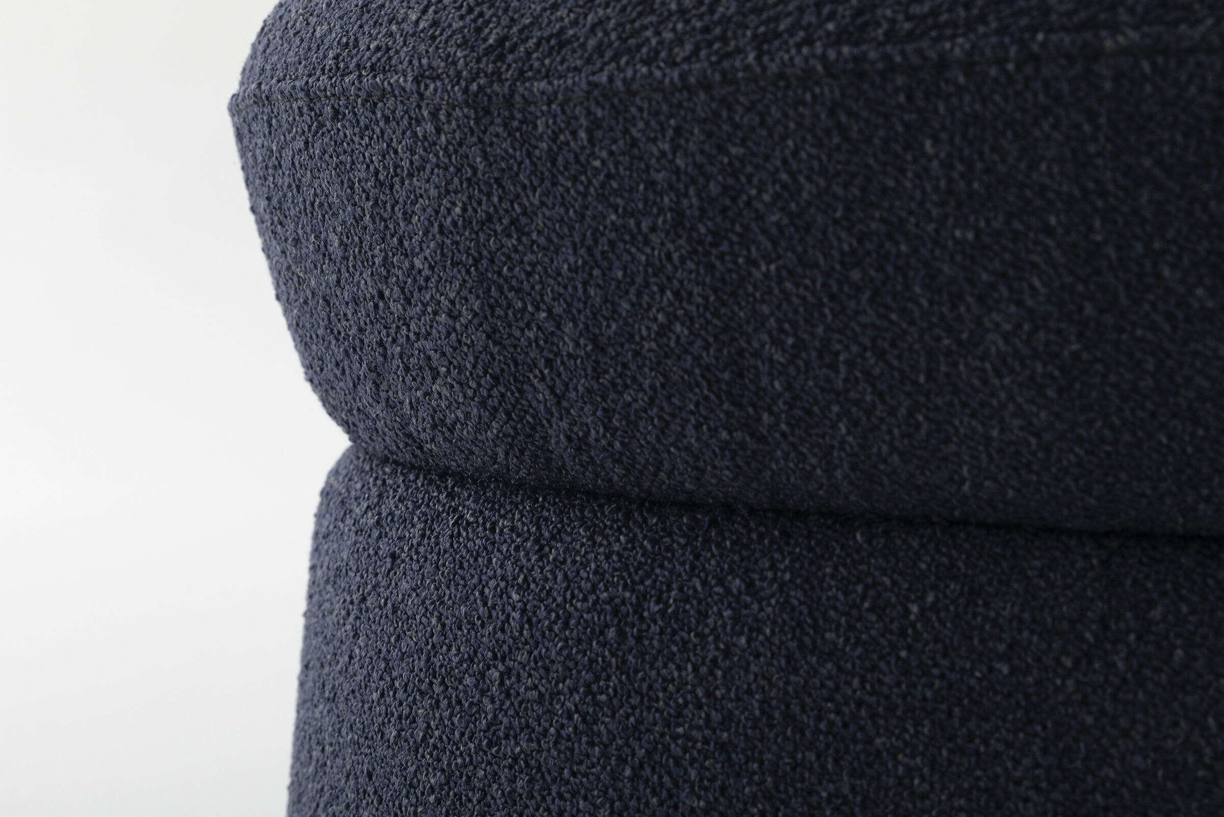 Soft navy blue textured upholstery fabric used in stylish modern furniture pieces.