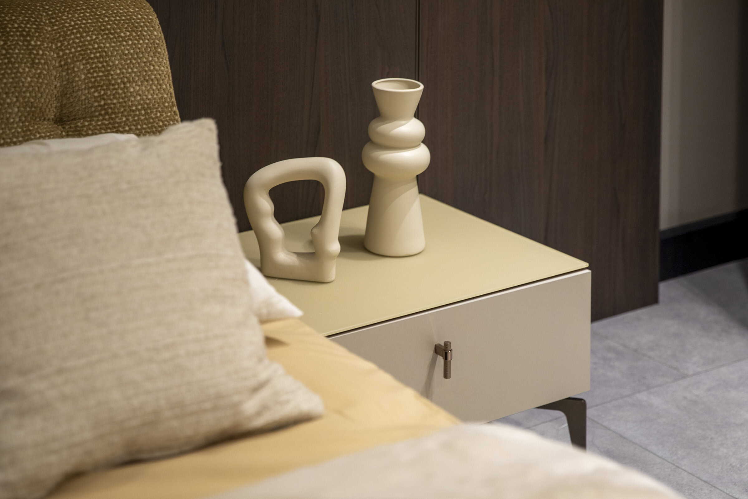 Sleek modern bedroom nightstand with minimalist beige finish and stylish ceramic decorative vases, perfect for contemporary home decor.