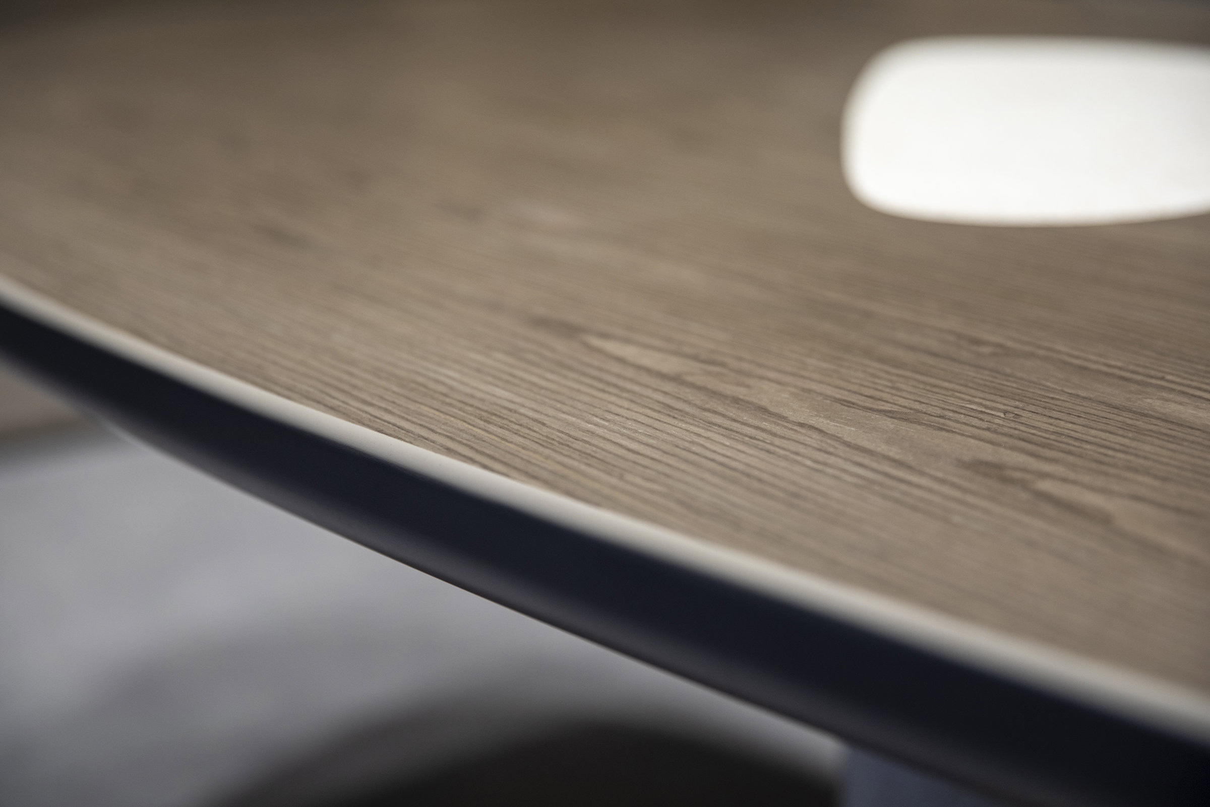 Polished wooden surface of modern furniture with sleek black edge detail, showcasing high-quality craftsmanship and contemporary design elements.