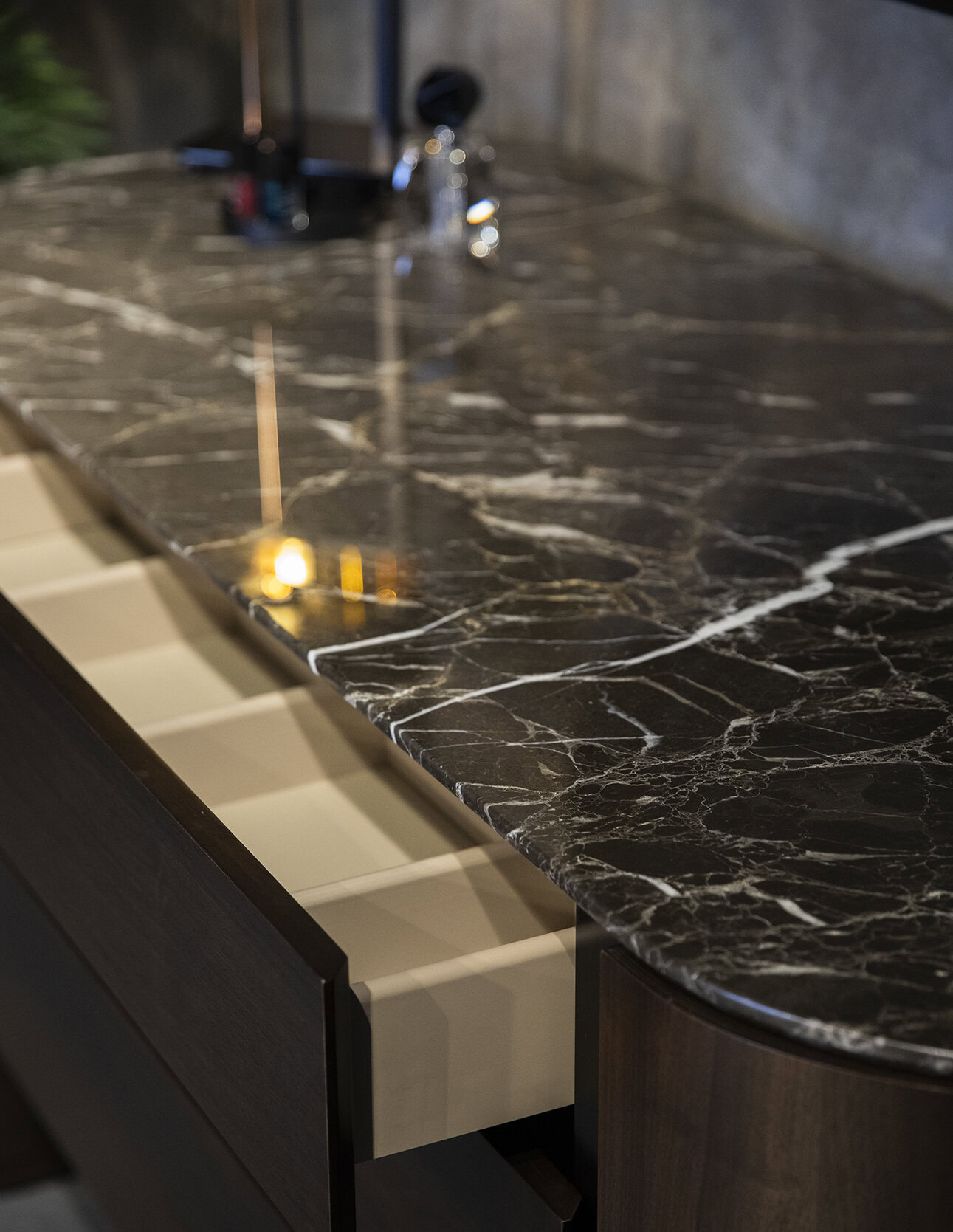 Luxurious dark brown marble kitchen countertop with white veining, sleek and polished, with modern cabinetry and sink fixtures for elegant kitchen design.