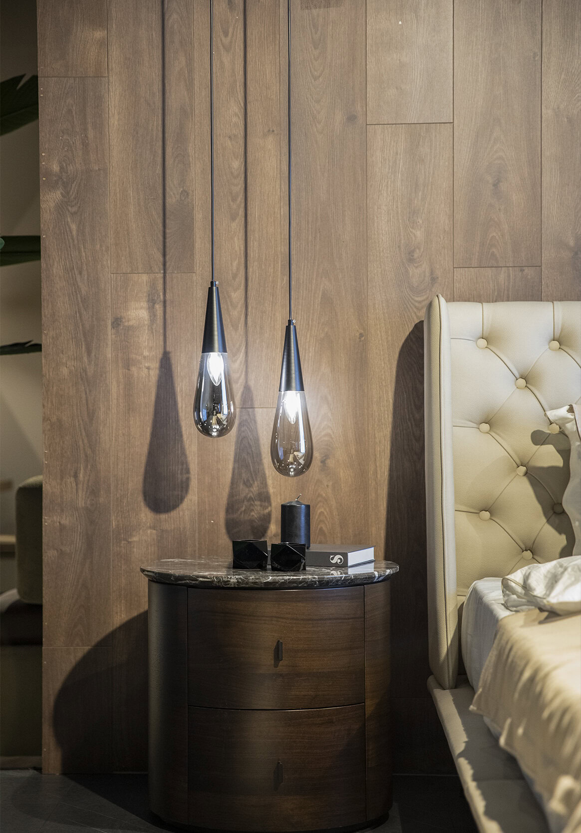 Contemporary bedroom with stylish pendant lights, wooden accent wall, and elegant nightstand, showcasing modern furniture design and luxury bedroom decor for a sophisticated interior aesthetic.