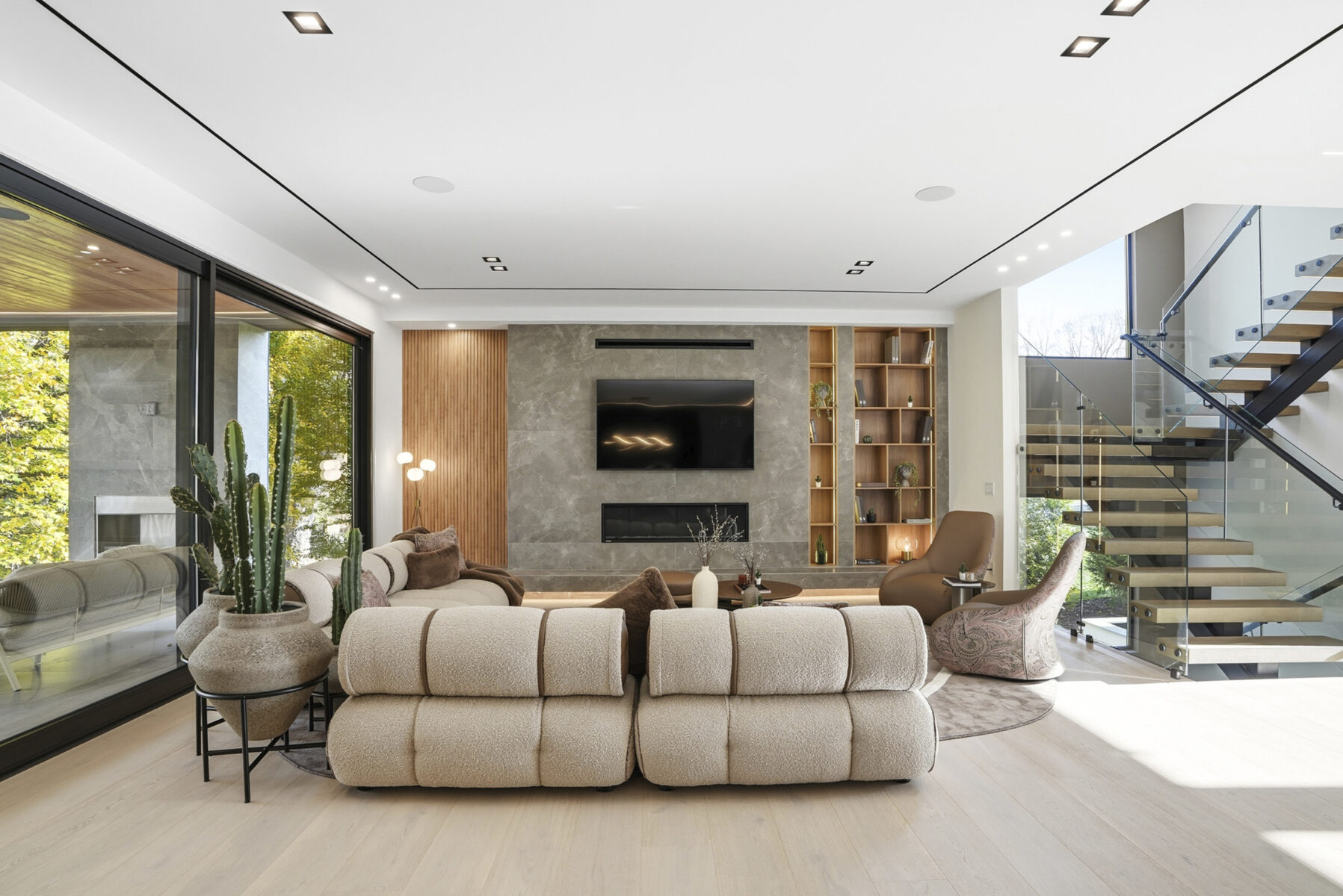 Elegant contemporary living room with plush beige sofa, stylish accent chairs, and sleek entertainment center showcasing Saloni Furniture designs. Bright, spacious, and perfect for modern homes.