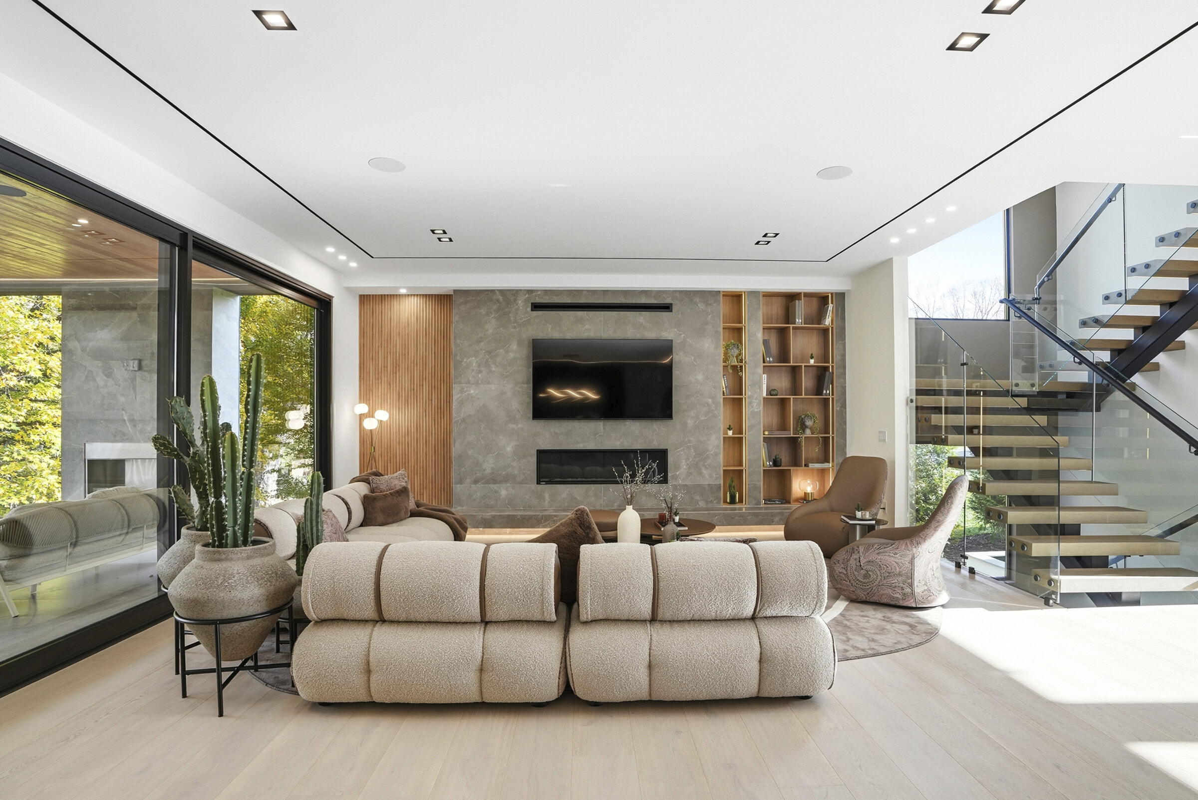 Elegant contemporary living room with plush beige sofa, stylish accent chairs, and sleek entertainment center showcasing Saloni Furniture designs. Bright, spacious, and perfect for modern homes.
