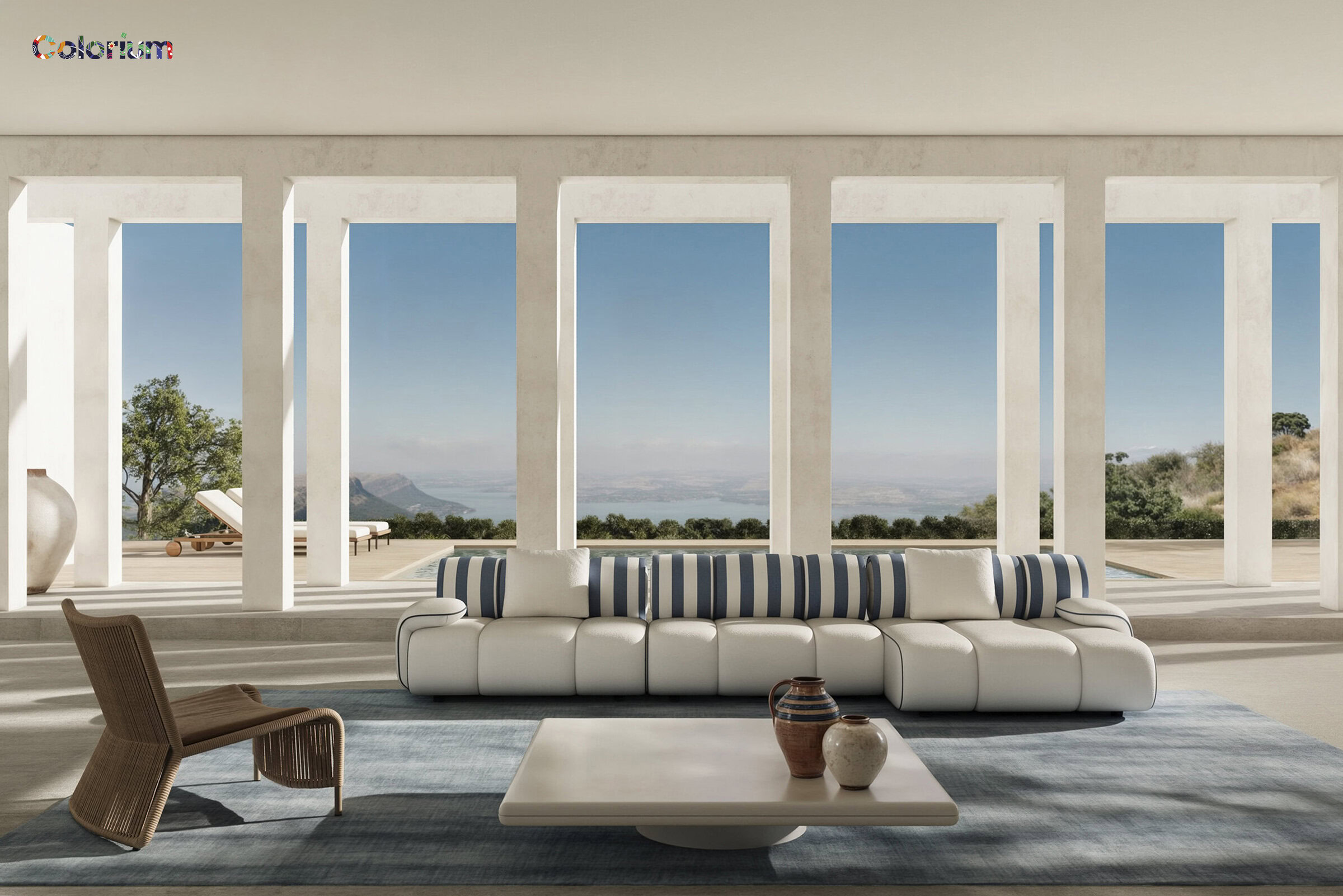 Modern living room with large floor-to-ceiling windows showcasing a scenic mountain view, featuring a stylish white sofa with blue striped cushions, a wooden chair, and a minimalist coffee table.