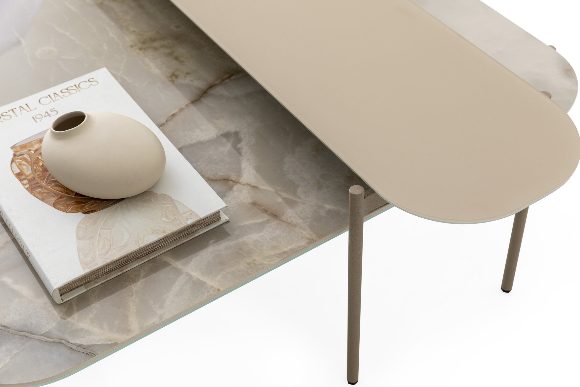 Minimalist coffee table with a beige oval top and slender legs, featuring a marble surface and decorative book with a small ceramic vase, perfect for modern living room decor.