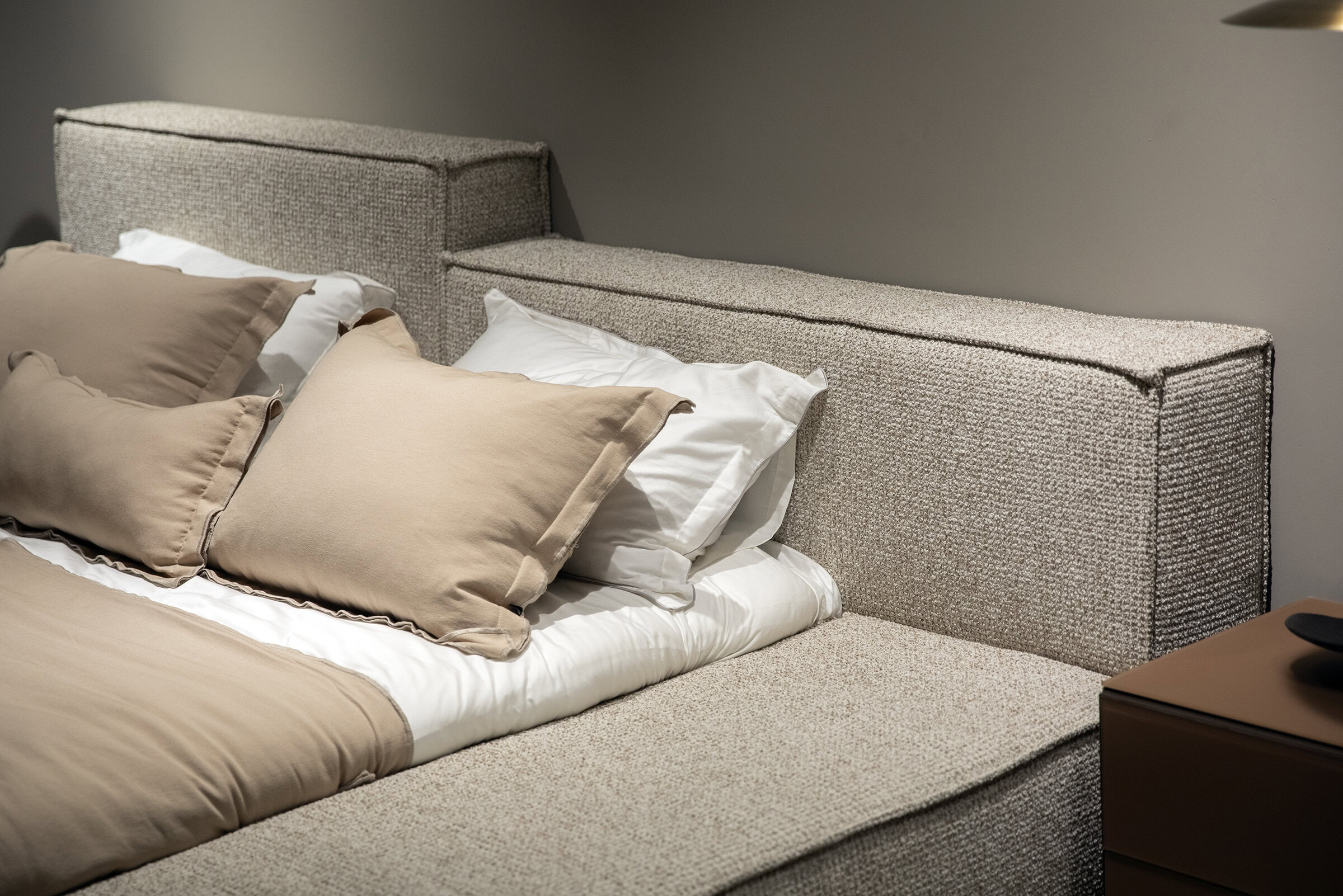 Luxurious upholstered bed with beige bedding and plush pillows, modern design, stylish headboard,Saloni Furniture bedroom furniture, elegant and comfortable sleep setup.