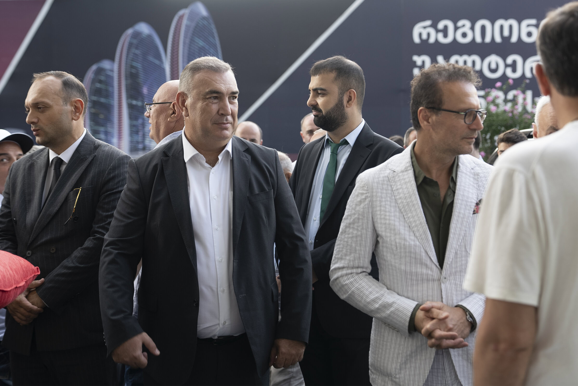 People attending a formal outdoor event in business attire at Saloni Furniture, showcasing professional networking, conference, or exhibition environment, with focus on modern furniture branding and corporate gathering.