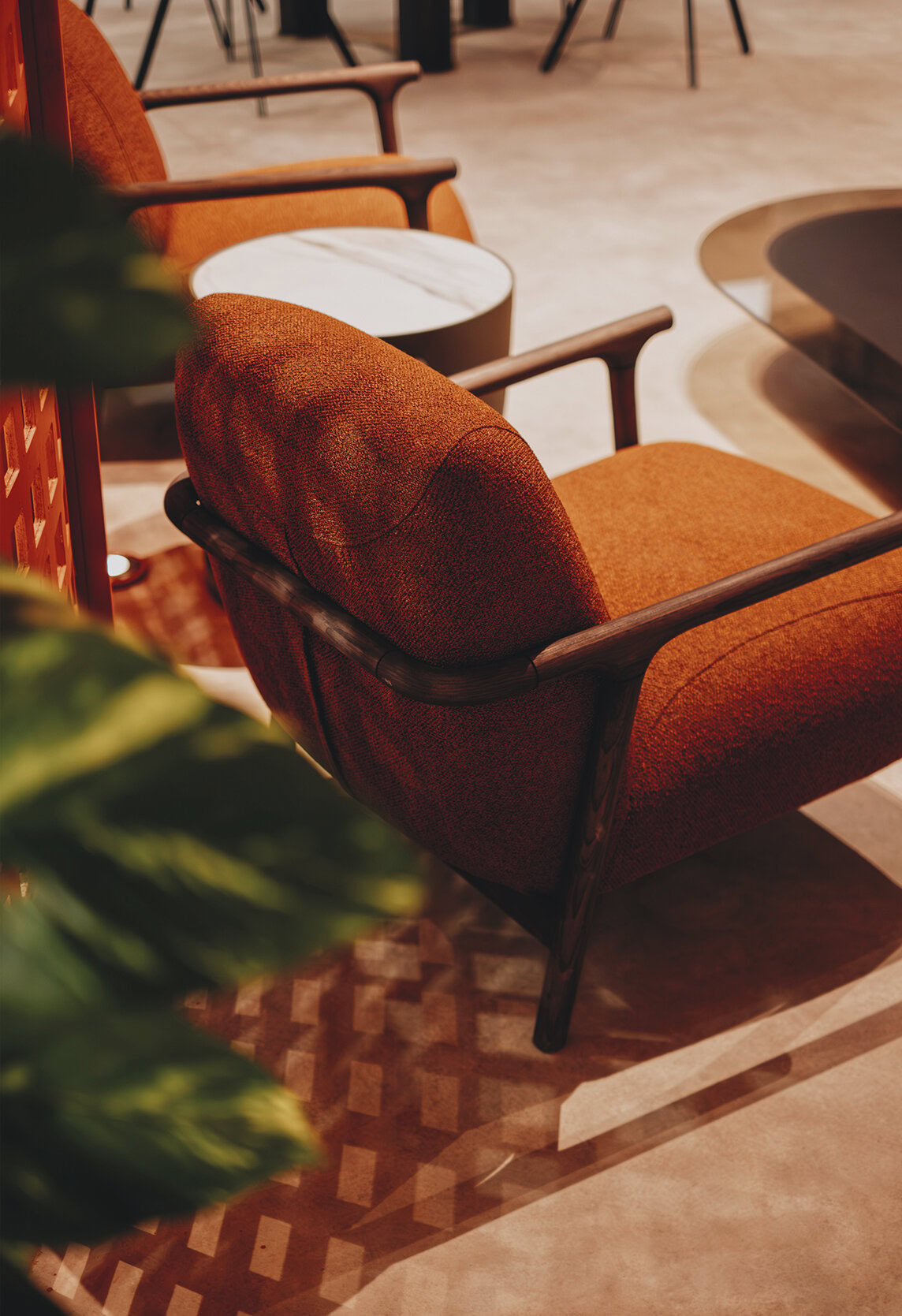 Elegant mid-century modern armchair with rich burnt orange upholstery and sleek dark wooden armrests, perfect for stylish living rooms and contemporary furniture design.