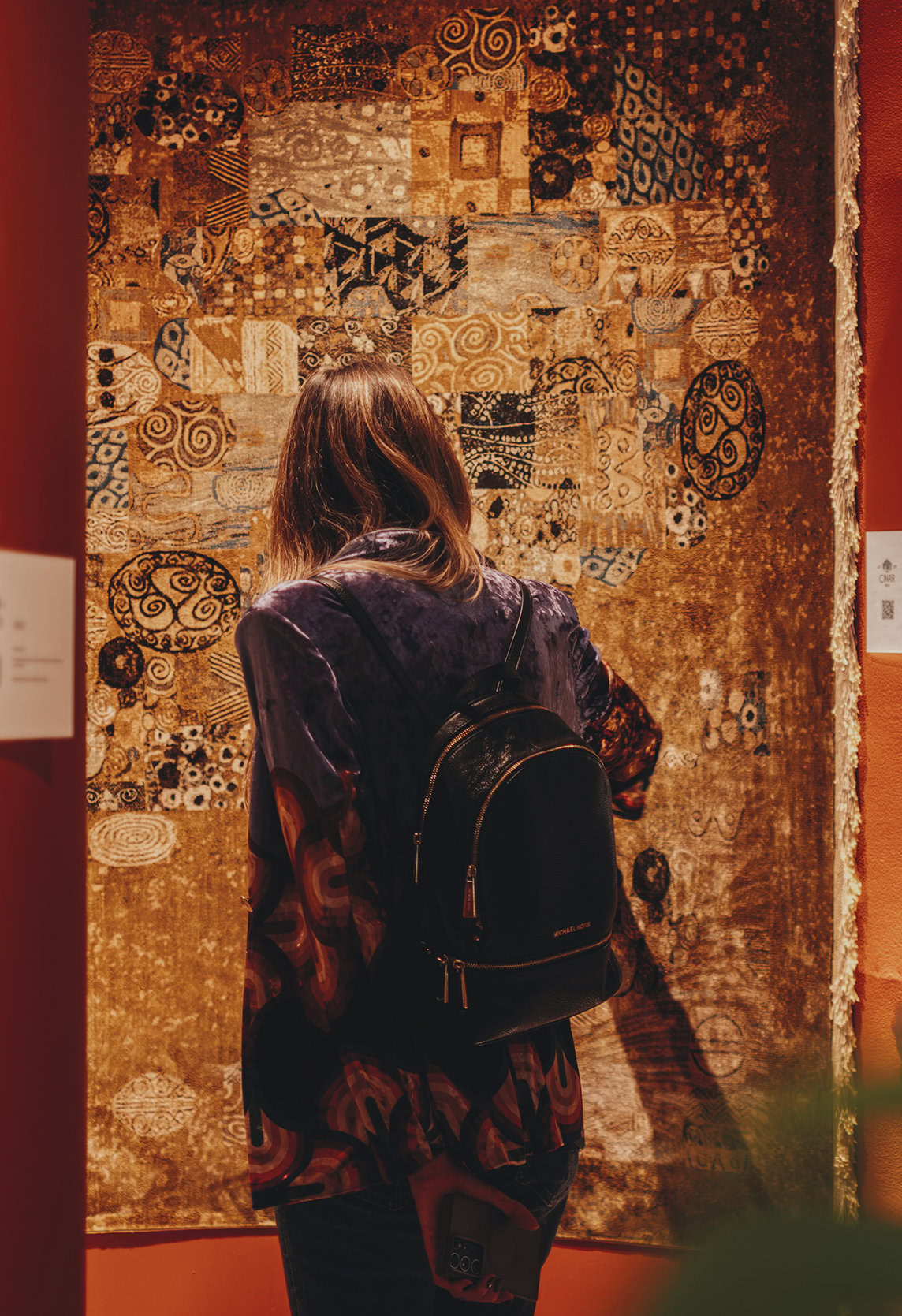 Intricately patterned textile art displayed in a modern gallery setting, showcasing Bohemian-inspired designs with rich textures and vibrant colors.