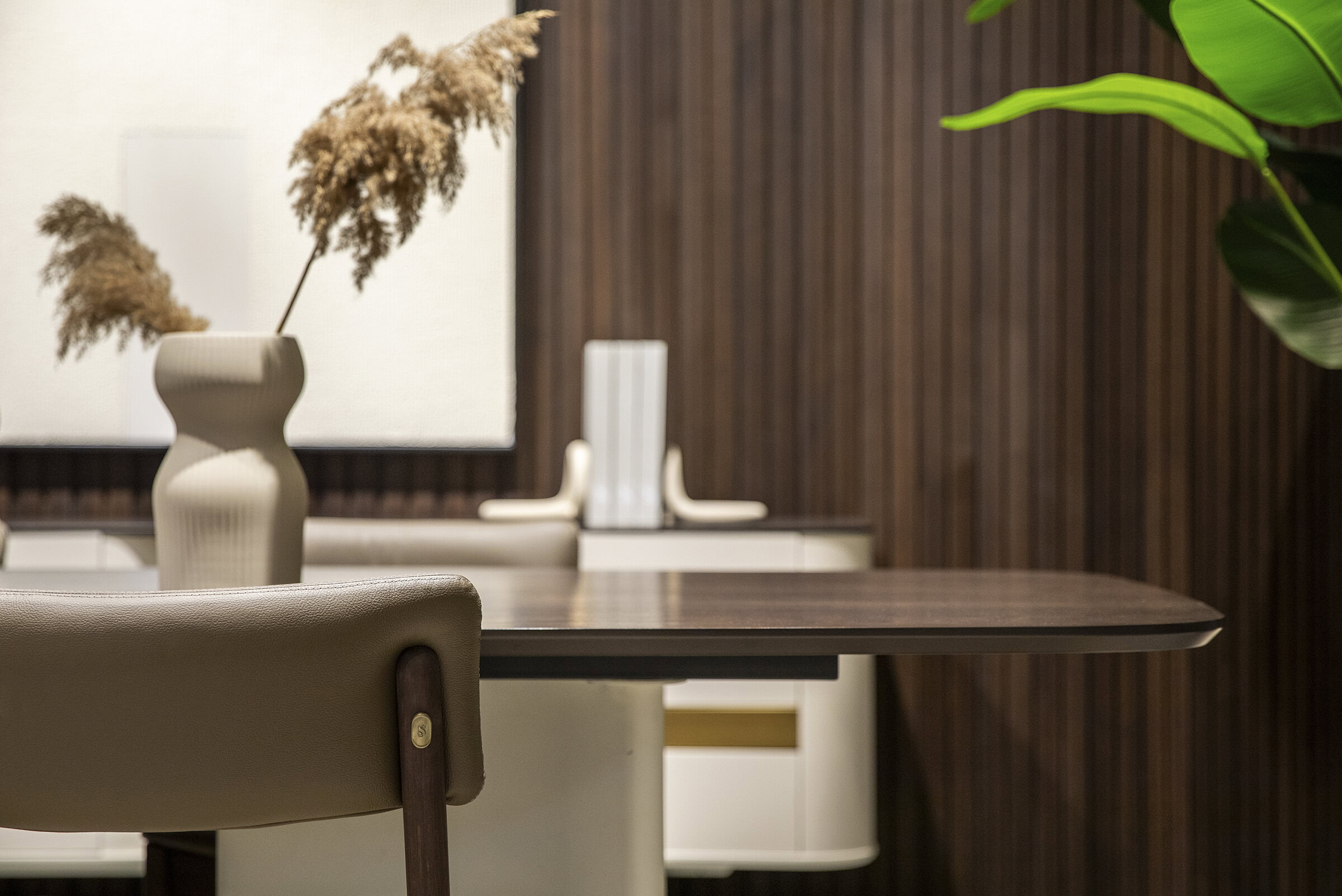 Contemporary dining room with modern furniture, featuring a dark wood dining table, elegant beige chairs, and decorative vases, creating a stylish and sophisticated ambiance.