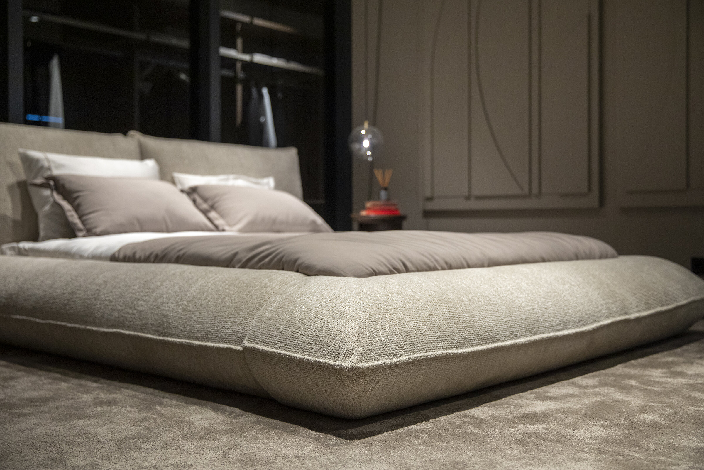 Luxurious beige upholstered bed with plush bedding in a modern bedroom featuring sophisticated decor and ambient lighting, perfect for stylish and comfortable bedroom furniture.