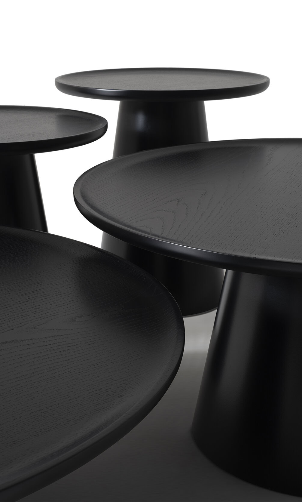 Sleek black minimalist coffee tables and side tables with smooth wooden surfaces and cone-shaped bases, ideal for modern living room decor and stylish interior design.